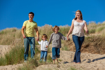 Mother, Father and Two Boys Family Walking in Sand Dunes on a Beach