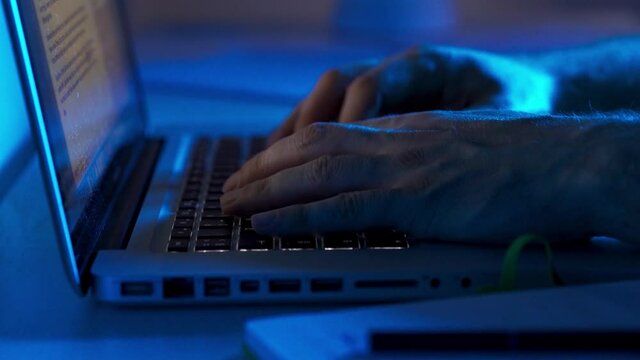 Man Hands Typing On Keyboard Of Laptop In Dark Room Light