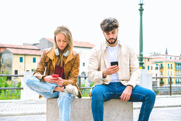 Multicultural group of friends using mobile phones - Students sitting in a row and typing on smartphones