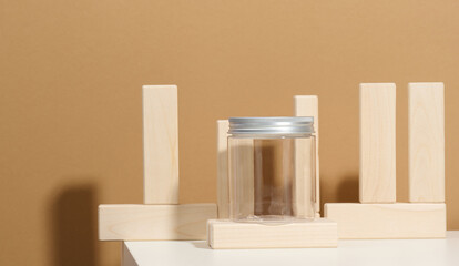 empty clear glass jar with aluminum lid on white table. Packaging for cream, gel, serum, advertising and product promotion, mock up