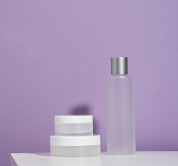 jar and empty white plastic tubes for cosmetics on a purple background. Packaging for cream, gel, serum, advertising and product promotion, mock up