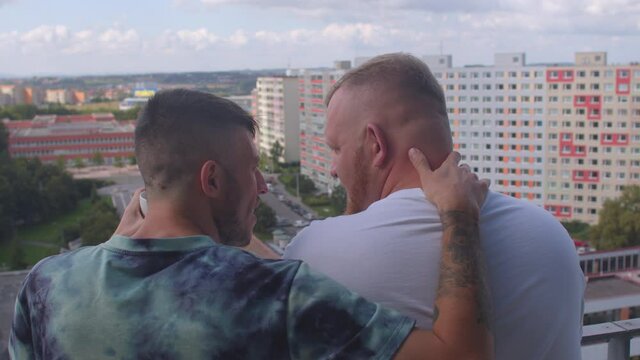 Real life. A loving couple of gays on the balcony greets a new day together, chatting sweetly, drinking tea from a small cup. Discussion of immediate plans. 