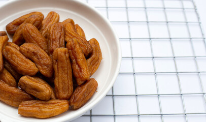 Sun-dried bananas in white plate on white background.