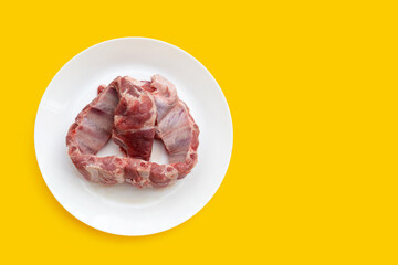 Raw pork ribs in white plate on yellow background.