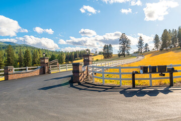 A winding gated road or path with white fence in a rural community of luxury homes on acreage at...
