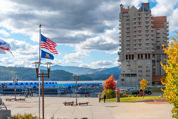 Tourists and locals enjoy an autumn afternoon at McEuen Park alongside the marina and hotel in downtown Coeur d'Alene, Idaho, USA.