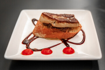 Artisanal pintxos or tapas of foie gras on a toast with balsamic glaze and onion jam on a plate in...