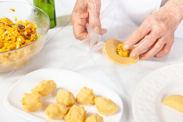 Preparation of the traditional patties from the region of Cauca in Colombia, called empanadas de pipián - Senior woman filling the patties