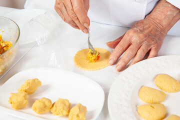 Preparation of the traditional patties from the region of Cauca in Colombia, called empanadas de pipián - Senior woman filling the patties