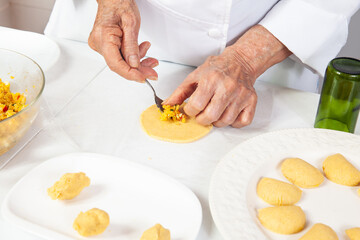 Preparation of the traditional patties from the region of Cauca in Colombia, called empanadas de pipián - Senior woman filling the patties