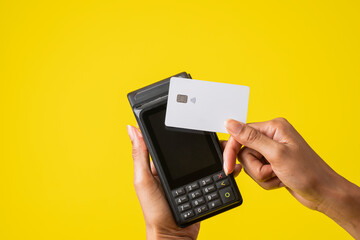 mano de una mujer afroamericana con un sistema de cobro con tarjeta de debito o crédito en sus manos - obrazy, fototapety, plakaty