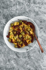 vegan spicy cous cous with sundried tomatoes and olives topped with coriander seeds and chilli flakes, healthy plant-based food