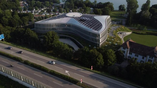 Slow aerial tilt up shot above a motorway and the International Olympic Committee building in Lausanne, Switzerland.