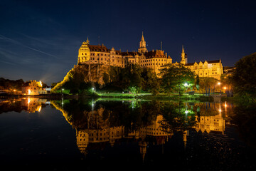 Obraz premium Hohenzollern Castle in Sigmaringen, Germany is reflected in the water of the Danube river at night