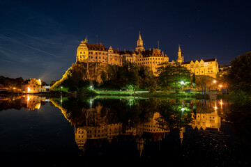 Fototapeta na wymiar Hohenzollern Castle in Sigmaringen, Germany is reflected in the water of the Danube river at night