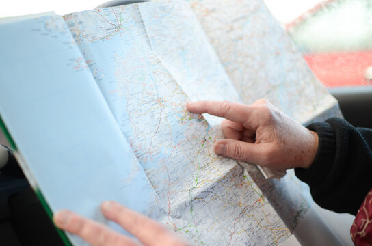 Older Woman Uses A Paper Map Of Ireland To Navigate Her Travels