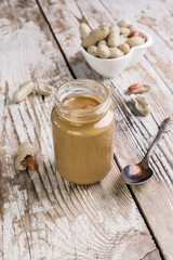 Peanut butter in a glass jar on a wooden background. Delicious and healthy breakfast.