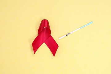 red ribbon and test pack symbol against HIV isolated on yellow background