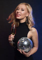 young woman holding a glass of wine and disco ball at night club