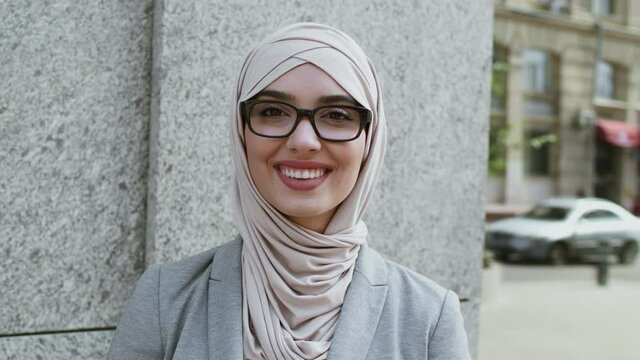 Business and eyesight concept. Beautiful middle eastern businesswoman in hijab wearing eyeglasses and smiling to camera
