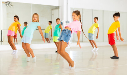 Kids warming up in group dance class, doing stretching exercises before dance training
