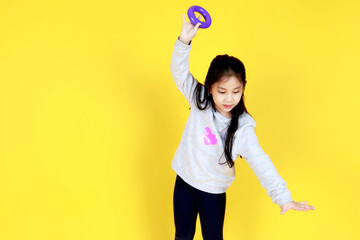 Cute litle Asian girl on sweater smile as enjoy playing children toy by raising hand high above...