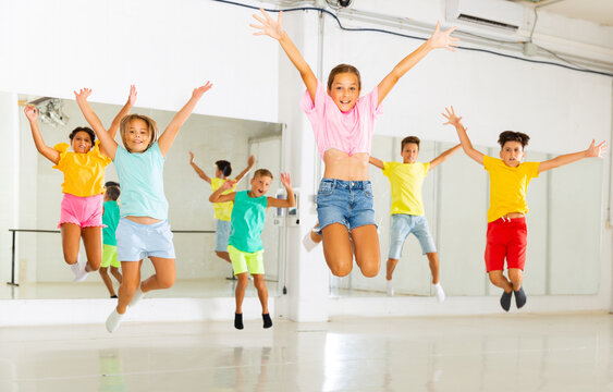 Happy children jumping while studying modern style dance in class indoors