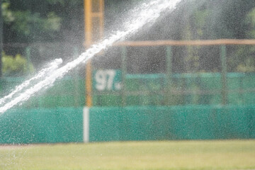 Water sprayed from a sprinkler during ground maintenance at a baseball field.