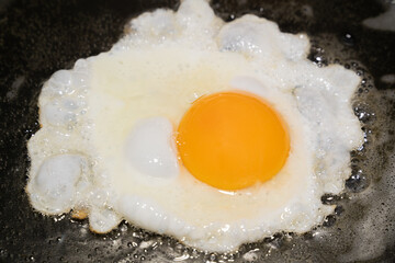 Fried egg fries on one side in the pan