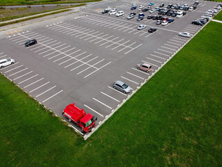 鳥の目線で見た上空からの駐車場の赤い車と緑の芝生