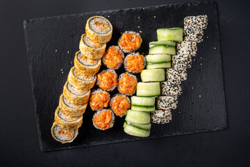Assortment of fresh prepared sushi on black background.