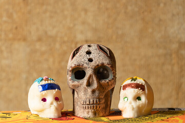 Traditional sugar skulls of the Mexican celebration of the Day of the Dead accompanied by a prehispanic clay skull