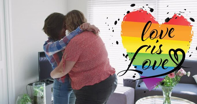 Animation of rainbow heart and love is love over lesbian couple embracing at home