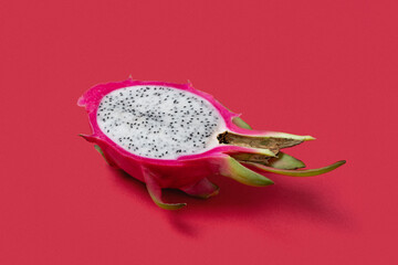 Dragon fruit cut in half in a plain red background