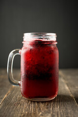 Blackberry cocktail with crushed ice in glass jar on the rustic wooden background. Selective focus. Shallow depth of field.