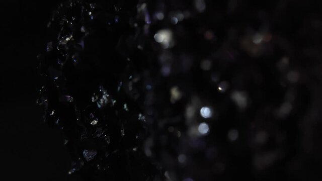 Closeup of dark, glittering covellite mineral stone, black background