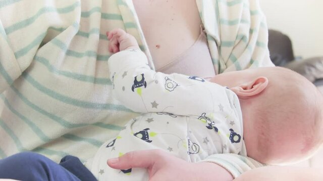 Baby in the fifth month of life sucking milk from the mother breast. Infant breastfeeding period.