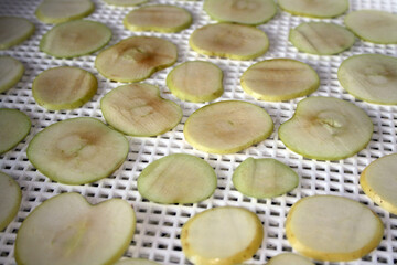 Slices of apples spread out on a tray for drying.