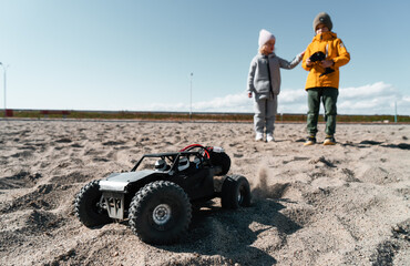 Playful baby kids driving radio controlled off road high speed sport buggy car on sand black SUV rc - obrazy, fototapety, plakaty