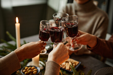 Close up of four people enjoying Christmas dinner together and toasting with wine glasses while...