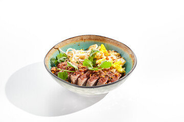 Pan asian traditional dish - fried rice with vegetables, shredded omelette and duck. Oriental wok with rice on white background. Nasi goreng with duck on isolated background with shadows.