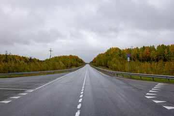 Autumn track on the border of the Khanty-Mansiysk Autonomous Okrug and the Sverdlovsk Region in Russia. A beautiful road in the fall between the Khanty-Mansi Autonomous Okrug and the Sverdlovsk Region