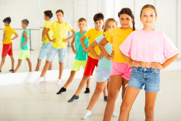 Obraz premium Group of positive children rehearsing movements of ballet in classroom