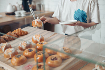 Young woman holding plate and pastry in cafe