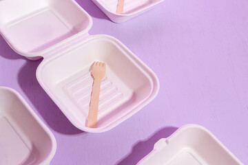 Empty packages with a wooden fork for bento cakes. Purple background with space for text. Selective focus.