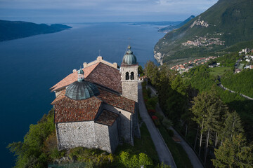 Fototapeta premium Panorama Eremo di Montecastello, Italy aerial view. Historic catholic church on the mountain, background of the Alps. 