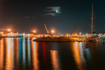 Fototapeta na wymiar Long exposure night photo in a harbor overlooking ships and warehouses.
