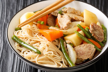 Nikujaga Japanese style meat and potatoes stew close up in bowl on the wooden table. Horizontal