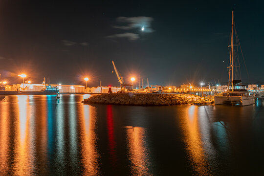 Long exposure night photo in a harbor overlooking ships and warehouses.