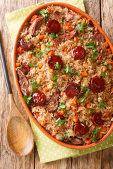 Arroz de pato or duck rice is a traditional Portuguese food close up in the baking dish on the wooden table. Vertical top view from above